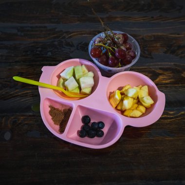 Çocuklar için eğlenceli yemek. Sağlıklı bir kahvaltı için elma, üzüm, yabanmersini ve guava şeklinde taze meyveli şirin bir araba tabağı..
