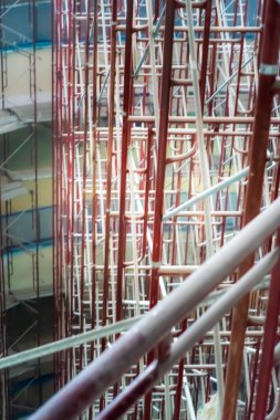 İskele platformlarının bulanık bir fotoğrafı. İnşaat halindeki iskeleli bir binada çalışma devam ediyor. Yeni Bina İnşaat Alanı