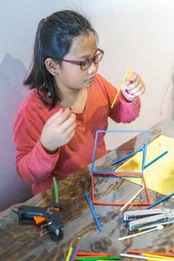 Genç bir kız bir sürü renkli plastik çubuklarla inşa ediyor. Geometrik figürler yapmak ve evde matematik öğrenmek eğlenceli. homeschool. 
