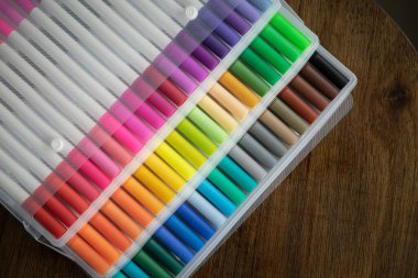 Tahta bir arka planda şeffaf plastik ambalajda 60 renkli işaret var..