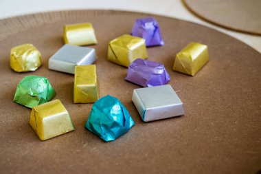 Kahverengi arka planda farklı tatlar için çeşitli renklerde paketlenmiş lüks çikolatalar..