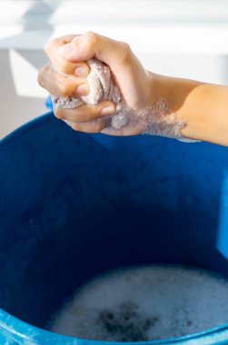 Sabun köpüğü ve mavi kovayla el bezi sağmak. Covid 19 salgını sırasında ev temizliği kavramı.