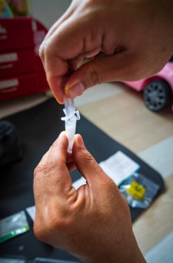 Tükürük için covid hızlı ev kullanımı test kiti - adım 2 - eller plastik tüp içinde ampul sıvısı doldurmaya çalışıyor