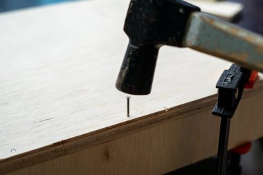 Marangozun atölyesinde çekiçle tahta üstüne çivi..