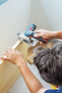 Tahtadaki elektronik testereyi kullanan bir adamın saçı..