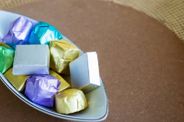 Farklı tatlar için çeşitli renklerde paketlenmiş lüks çikolatalar kahverengi arka planda bir kasede..