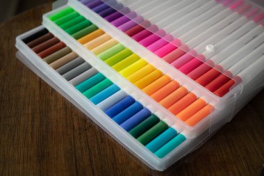 Tahta bir arka planda şeffaf plastik ambalajda 60 renkli işaret var..