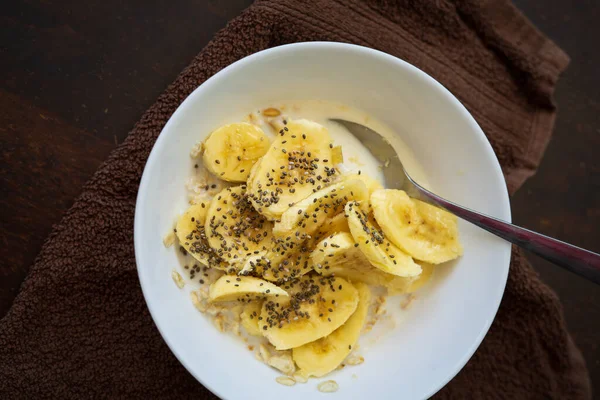 Zbliżenie Miski Zbóż Plasterkami Bananów Posypane Nasionami Chia Misce Ciemnym — Zdjęcie stockowe