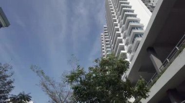 Rüzgâr tarafından sallanan ağaçlar ve arka planda modern bir daire. Düşük açı.