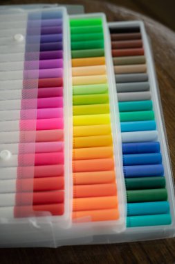 Tahta bir arka planda şeffaf plastik ambalajda 60 renkli işaret var..