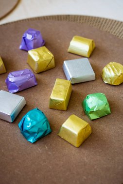 Kahverengi arka planda farklı tatlar için çeşitli renklerde paketlenmiş lüks çikolatalar..