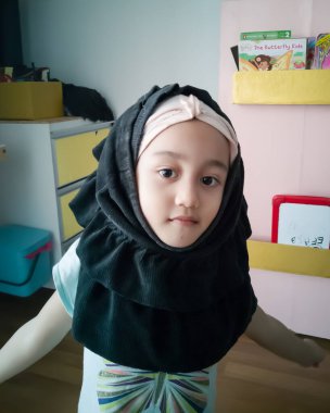 Kızıl bezle kaplı genç bir müslüman kızın portresi kameraya bakıyor, gülümsüyor, mutlu ve boşluğu kopyalıyor.