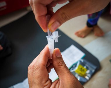 Tükürük için covid hızlı ev kullanımı test kitinin bulanık fotoğrafı - adım 2 - plastik tüp içinde ampulün test sıvısını doldur