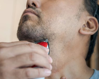 Elektrikli tıraş makinesiyle sakal tıraşı olan bir adam. Yakın plan..