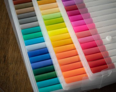Tahta bir arka planda şeffaf plastik ambalajda 60 renkli işaret var..