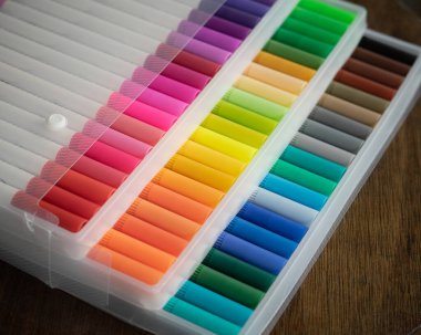 Tahta bir arka planda şeffaf plastik ambalajda 60 renkli işaret var..