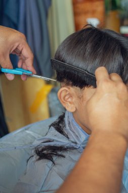 Tanımlanamayan çocuk saçını kestiriyor. Yakın çekim..