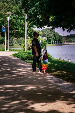 Bir babanın ve kızının yüz maskesi takıp gölün parkında dikilirken görüntüsü..