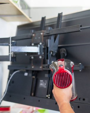 Evdeki televizyonun arkasını temizleyen bir adam..