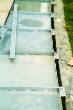 İnşaat alanında metal su boşaltma ya da hendek. Oluklar ızgara ızgarası, kanalizasyon kapağı. Bahçe giderleri - kanalizasyon kapağı. Su, metalin altındaki drenaja gider..