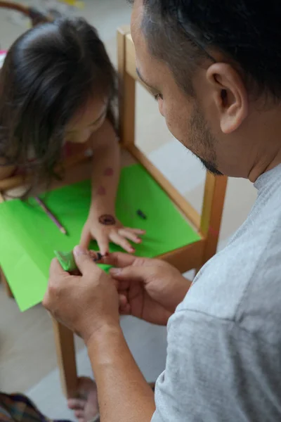 娘の手にヘナの装飾品を描く父 — ストック写真