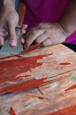 Eski masa temizleme sözcüsünün elinde skapele, egzotik ahşap talaş tahtası talaşı var.