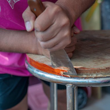 Eski masa temizleme sözcüsünün elinde skapele, egzotik ahşap talaş tahtası talaşı var.