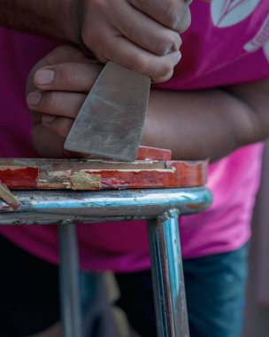 Eski masa temizleme sözcüsünün elinde skapele, egzotik ahşap talaş tahtası talaşı var.