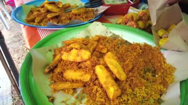 Bangi, Malezya - Mart 2021: Müşteri için kızarmış muz veya goreng pisang paketleyen sokak yemekleri satıcısı. El bilgisayarı. Görüntü düşük ışıktan dolayı gürültü içerebilir.