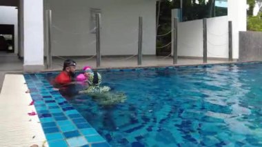 Baba çocuğu suya atıyor. Asyalı aile açık havuzda eğleniyor. Aktif çocuklar. Görüntü düşük ışıktan dolayı gürültü içerebilir.