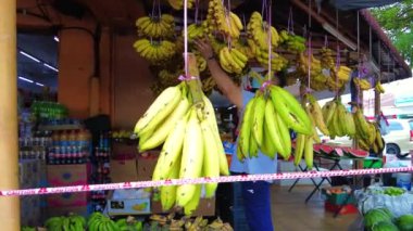 Bangi, Malezya - Mart 2021: Yüzü maskeli bir adamla dükkanda sallanan muzlar