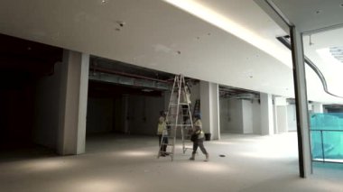 Kuala Lumpur, Malezya - 15 Nisan 2021 Bir alışveriş merkezi şantiyesine yangın detektörü yerleştiren işçiler.