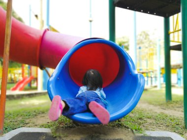 Çocuk oyun parkında bir kaydırağın dibinde oynuyor..