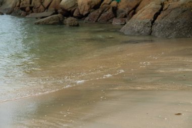 Kumsalın arka planında köpüklü yumuşak dalgalar.