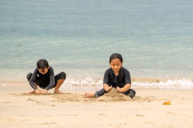 Genç Asyalı çocuklar sahilde oynuyorlar. Tatil ve rahatlama kavramı.