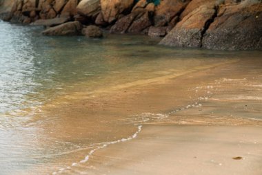 Kumsalın arka planında köpüklü yumuşak dalgalar.