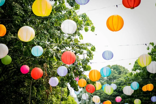 Arkaplanda ağaçlar ve gökyüzü asılı renkli kağıt fener..