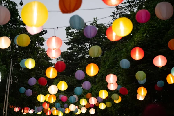 Arkaplanda ağaçlar ve gökyüzü asılı renkli kağıt fener..