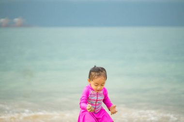Sahilde oynayan küçük Asyalı kız. Tatil ve rahatlama konsepti..