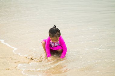 Sahilde oynayan küçük Asyalı kız. Tatil ve rahatlama konsepti..