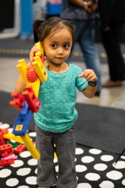 Asyalı çocuk içeride renkli oyuncaklar oynuyor..