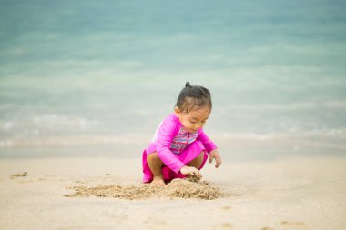 Sahilde oynayan küçük Asyalı kız. Tatil ve rahatlama konsepti..