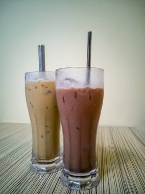 Buzlu kahveyle dolu bir bardak üzerinde, yeniden kullanılabilir bir metalle, ahşap bir restoranın masasında pipet içerken yaklaş.