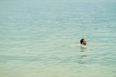 Sakallı adam denizde yüzüyor. Minimalizm kavramı.