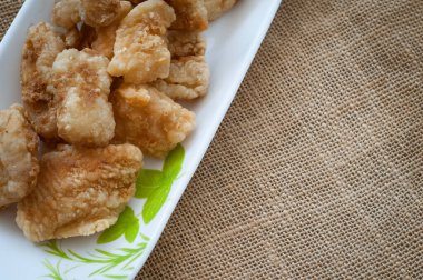 Malezya usulü dövülmüş ve kızartılmış dory balığı küpleri. Kahverengi arka planda uzun bir tabakta servis edilmiş.