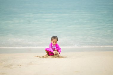 Sahilde oynayan küçük Asyalı kız. Tatil ve rahatlama konsepti..