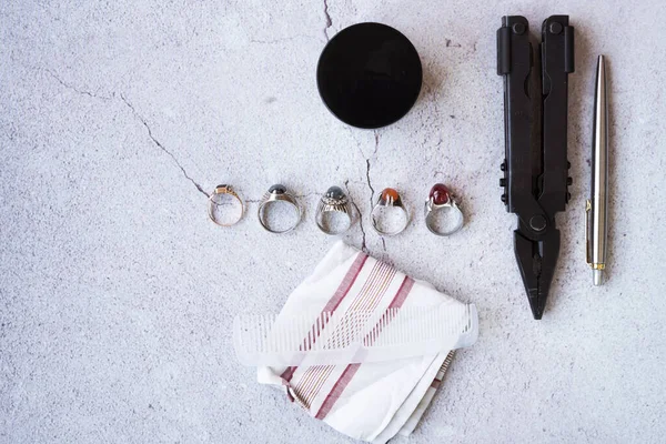 Şık erkek yüzükleri, kalem, aletler, mendil, poz ve tımar için parfüm. Beton arka planda metroseksüel sezaryenler. Şehir kompozisyonu. Üst görünüm.