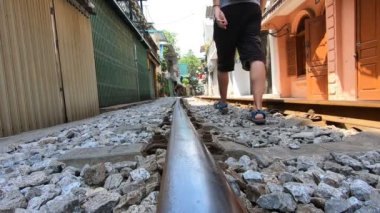 Adam Hanoi 'de bir yerleşim bölgesinde demiryolunda yürüyor.