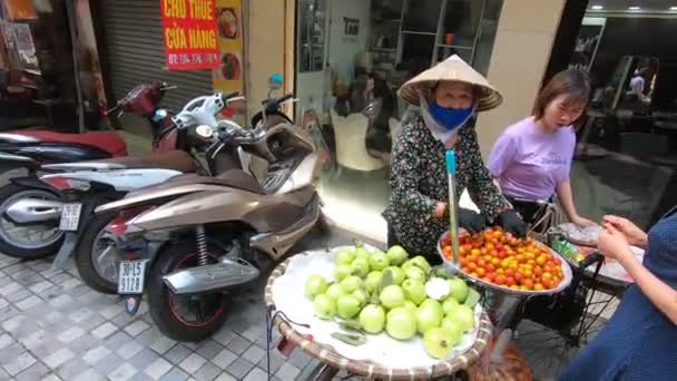 Straatverkoper in een traditionele conus hoed verkoopt fruit van een fiets in Vietnam — Stockvideo