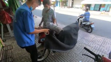 İki adam yollamak için bir motosiklet hazırlıyor. Saygon, Vietnam